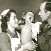 (Sgt.) KM Hermiston of the CWAC Film and Photo Unit took this picture of child being examined by a doctor and Red Cross Nurse on February 5, 1946.